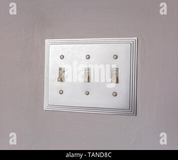 Close up of the electrical light switch against the white wall of a house. The vertical flip toggle light switches is in off mode. Stock Photo