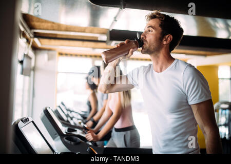 Handsome sporty man resting, having break drinking water after doing exercise Stock Photo