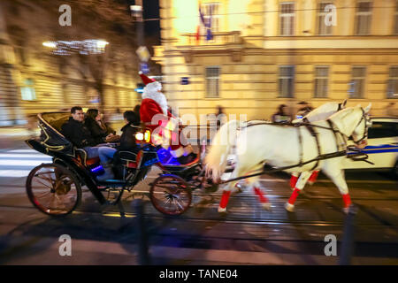 Zagreb, Croatia - December 13, 2018: People driving in a carriage with horses and a man dressed in a Santa Claus suit as a driver on the street of Zag Stock Photo