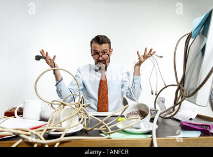 Completely confused. There are a lot of wires in the workplace and man is constantly tangled in them. It's literally blocking him. Concept of office w Stock Photo