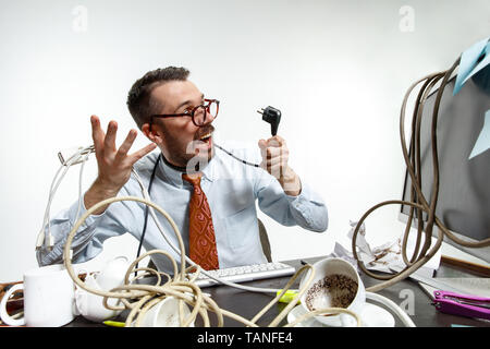 Completely confused. There are a lot of wires in the workplace and man is constantly tangled in them. It's literally blocking him. Concept of office w Stock Photo