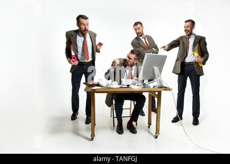 Internal problems. The young man suffering form colleagues laughing at him and constantly discussing. Phycology and mental pressed. Concept of office  Stock Photo