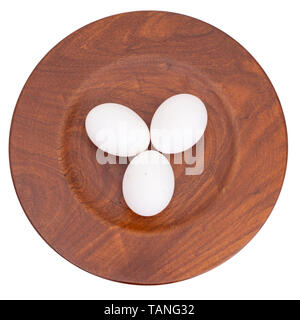 Three white chicken, hens eggs on wooden plate isolated on white. Stock Photo