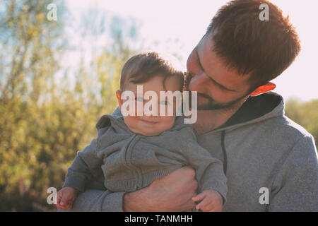 Cute baby boy on his dad's shoulders walking on road outdoors, sensitivity to the nature concept Stock Photo