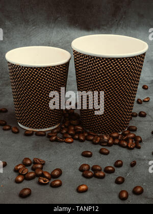 two beautiful disposable paper coffee cups with beans on concrete background, with filter Stock Photo