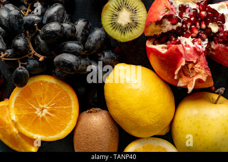 abstract background with fresh organic fruits such as sliced orange kiwi grapes and garnets