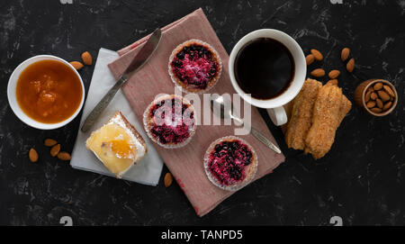 selection of sweet cakes, cupcake and cheesecake, hot coffe on the table, almond nuts in a bowls Stock Photo