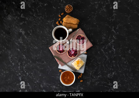 selection of sweet cakes, cupcake and cheesecake, hot coffe on the table, almond nuts in a bowls Stock Photo