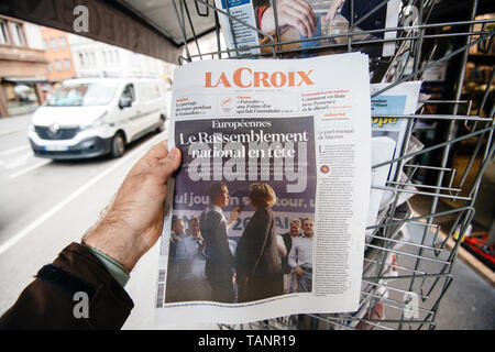 Strasbourg, France - May 27, 2019: Man holding buying La Croix newspaper front page on street press kiosk newsstand with the results of 2019 European Parliament election  Stock Photo
