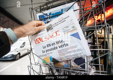 Strasbourg, France - May 27, 2019: Man holding buying l'alsace newspaper front page on street press kiosk newsstand with the results of 2019 European Parliament election  Stock Photo