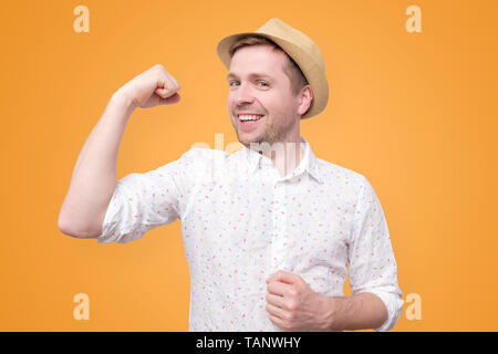 Young funny tourist man in summer hat shows biceps Stock Photo