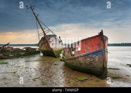 Old boat wrecks under a stormy sky on the River Orwell at Pin Mill on the Suffolk coast Stock Photo