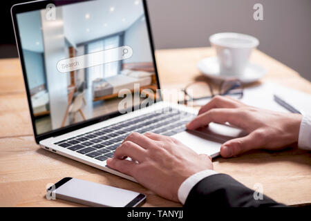 Buisiness man hand on table using a laptop with hotel room booking with search bar Stock Photo