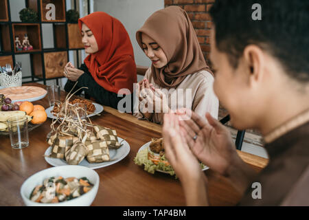 Hijab women and a man pray together before meals Stock Photo