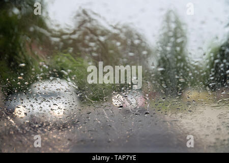 Rain drops on front car window, driving in heavy rain. Pouring rain, water drops on window. Concept of windshield not working, dangerous driving Stock Photo