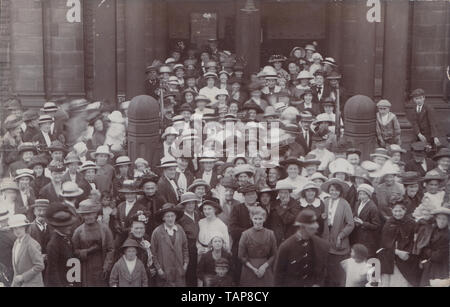 Vintage British Photographic Postcard Showing a Large Group of People Coming Out of an Imposing Public Building. Stock Photo