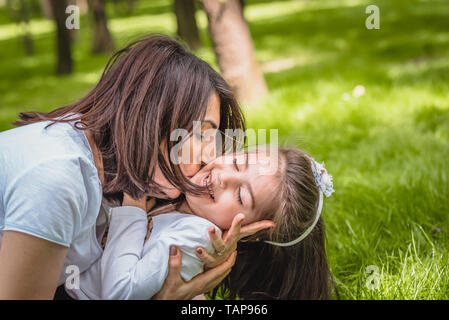 Young mom hugs and kisses her daughter showing love and support, caring young mother embrace girl.Happy mother hugging her daughter with love and natu Stock Photo