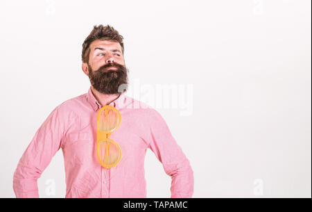 Man with beard and mustache on thoughtful face wear funny eyeglasses as tie, white background. Guy with beard in wear glasses as tie. Optics and glasses concept. Hipster with giant striped sunglasses. Stock Photo