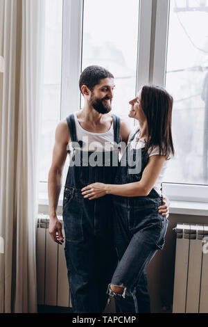 happy young couple standing near the window and looking to each other Stock Photo