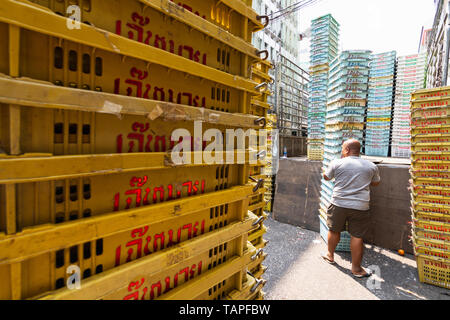 BANGKOK, THAILAND - MARCH 2019: man unloading empty plastic crates at the market street. Stock Photo