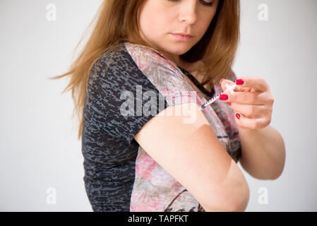Diabetes dependent female doing human insulin vaccination shot Stock Photo