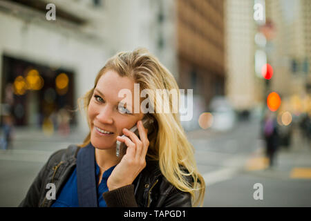 Portrait of a cheerful young woman talking on her cellphone. Stock Photo