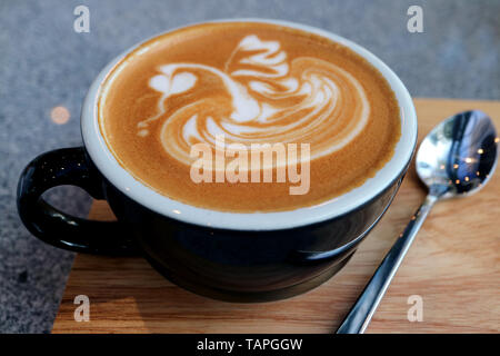 Closeup a Cup of Hot Cappuccino Coffee with Tea Spoon Served on Wooden Tray Stock Photo