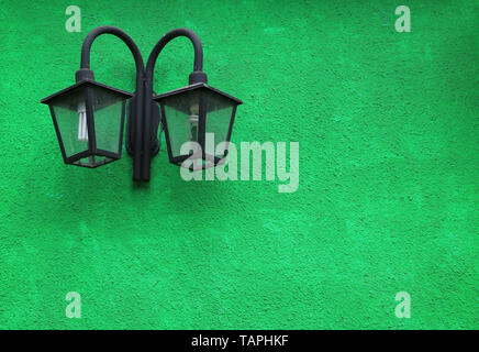 Pair of Black Retro Street Lamps on the Vivid Green Colored Concrete Wall Stock Photo