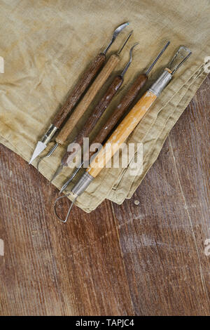 Close-up of various sculpting tools for clay modelling on dirty napkin placed on wooden table Stock Photo