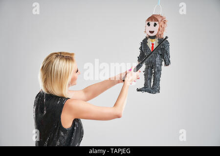 Picture of woman hitting male pinata over grey background Stock Photo