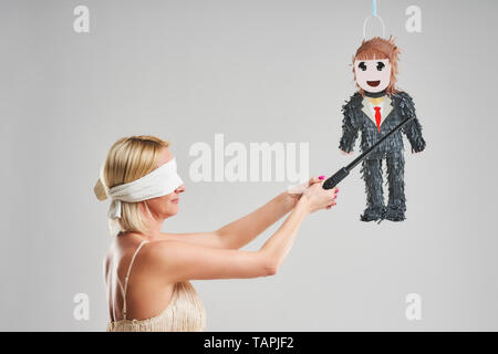 Picture of woman hitting male pinata over grey background Stock Photo