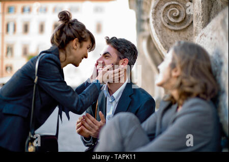 Happy young businesswoman playfully holding the face of a colleague. Stock Photo
