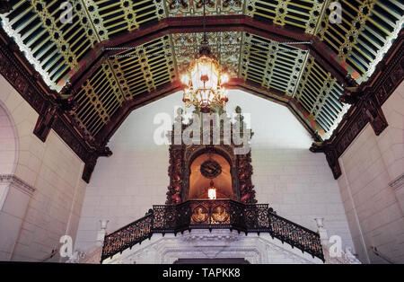Beneath a Moorish wood-beamed ceiling is a huge Spanish baroque doorway leading to lavish ballrooms in the historic Millennium Biltmore Hotel that opened in 1923 on Pershing Square in the heart of downtown Los Angeles, California, USA. A chandelier imported from Italy more than 95 years ago shines on two golden figures on the stairway balustrade, the Roman goddess of agriculture, Ceres, and the Spanish explorer Vasco Núñez de Balboa. This view is enjoyed by guests who meet in the Rendezvous Court, once the opulent lobby of the 11-story hotel and a location for Hollywood movies and TV shows. Stock Photo