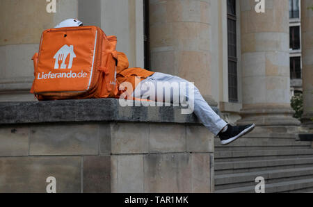 Berlin, Germany. 05th May, 2019. An employee of the delivery service Lieferando lies on a concrete pedestal at Gendarmenmarkt and rests. Credit: Paul Zinken/dpa/Alamy Live News Stock Photo