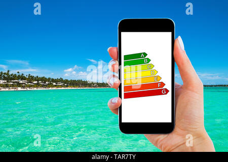 Hand holding digital smartphone with house efficiency rating. Detail of house efficiency rating on digital tablet screen. Concept of ecological and bi Stock Photo