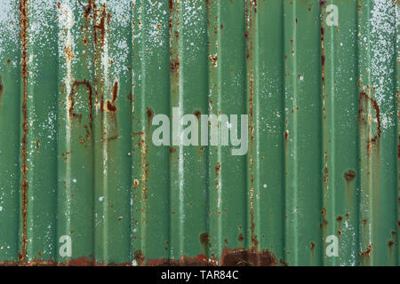 Green rusty metal fence. Corrugated metal sheet. Wall of green freight container. Vintage creative background Stock Photo