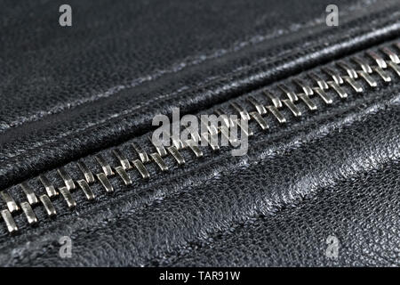 Macro shot of zipper on black leather texture background with stitching. Horizontal background from a close-up of black leather material Stock Photo