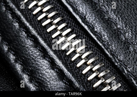 Macro shot of zipper on black leather texture background with stitching. Horizontal background from a close-up of black leather material Stock Photo