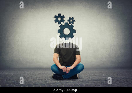Surreal headless guy, invisible face seated on the floor with gears instead of head, as a brain mechanism symbol. Mind cogwheels working system, conne Stock Photo