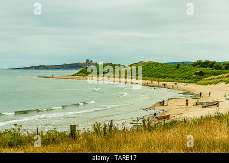 The beach at Low Newton-by-the-Sea on an overcast summer day with Dunstanburgh Castle ruins in the background. Northumberland, UK. July 2018. Stock Photo