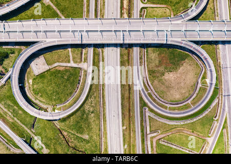 Big empty road junction on green land aerial view. Highway and half clover leaf junction with traffic