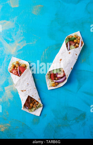 Vegan wraps in pita with chickpeas and mashed avocado on blue background Stock Photo