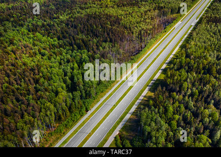 Straight empty highway through deep forest aerial view. Bright summer image at sunny day Stock Photo