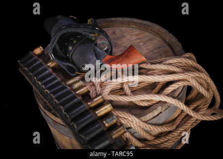 Old wild west gun with cartridges and gunbelt on wooden barrel Stock Photo