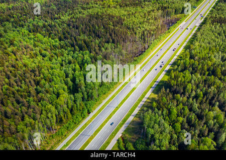 Straight highway through deep forest aerial view. Bright summer image at sunny day Stock Photo