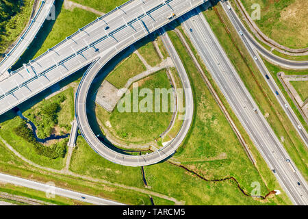 Big road junction fragment on green land aerial view, Highway intersection with traffic at sunny day