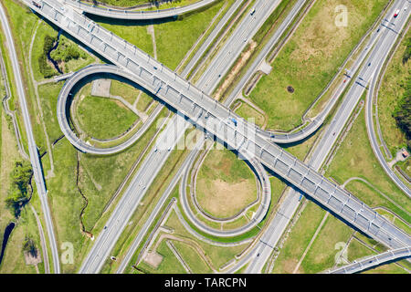 Big road junction on green land aerial view. Highway and half clover leaf junction with traffic