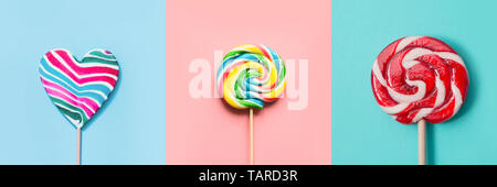 Three colorful lollipops candy as heart and swirl on blue and pink. Funny concept. Top view. Collage. Stock Photo