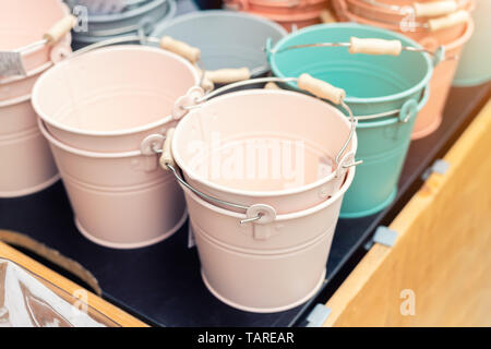 Various multicolored bright small ornamental metal buckets for sale on wooden table outdoors. Many colorful decorative mini pails for garden flower Stock Photo