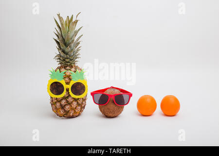 Pineapples and a coconut wearing sunglasses on white background. Summer concept Stock Photo